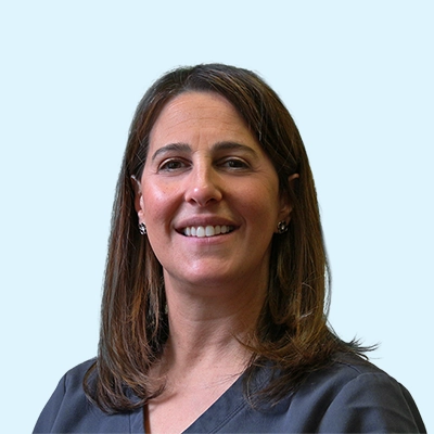 Robin L. Steinberg smiling with a light blue background.